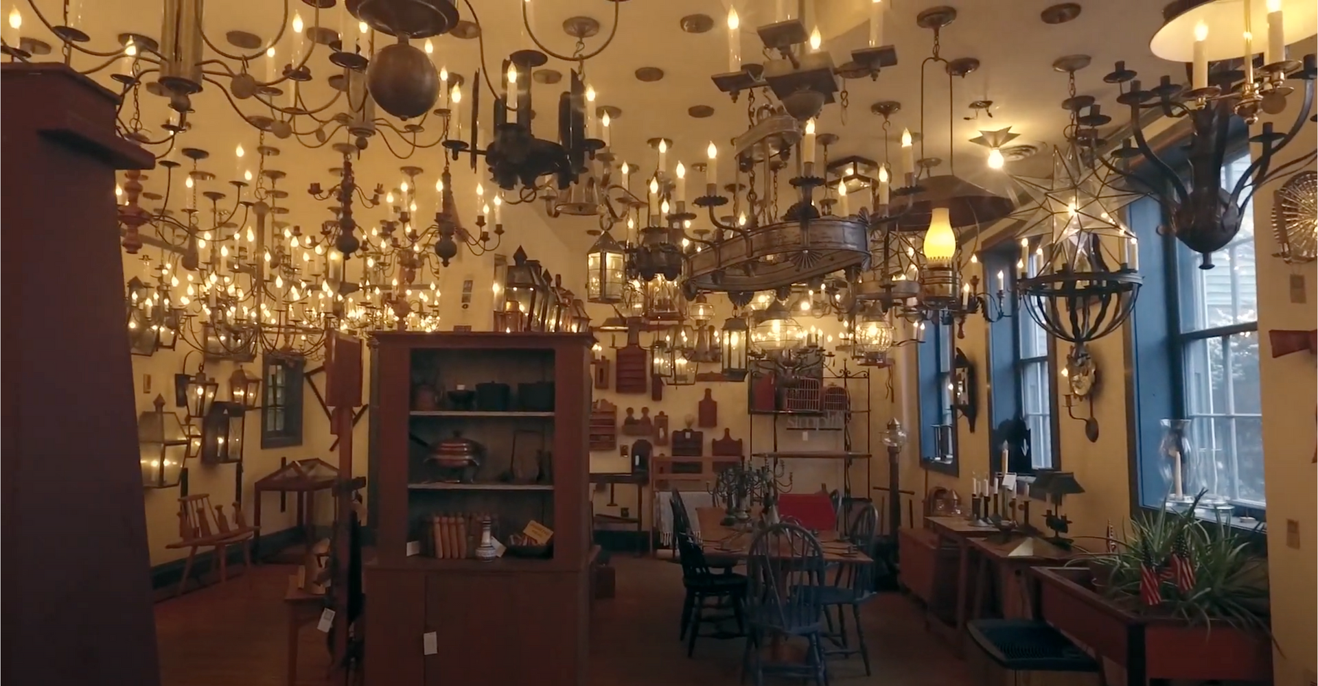 Load video: Our virtual showroom tour gives customers a chance to peruse all that we have on offer from the comfort of their own home. Glistening chandeliers, sparkling sconces and lanterns adorn every inch of the ceiling and walls. Hand-built wooden and metal furniture fill the space.